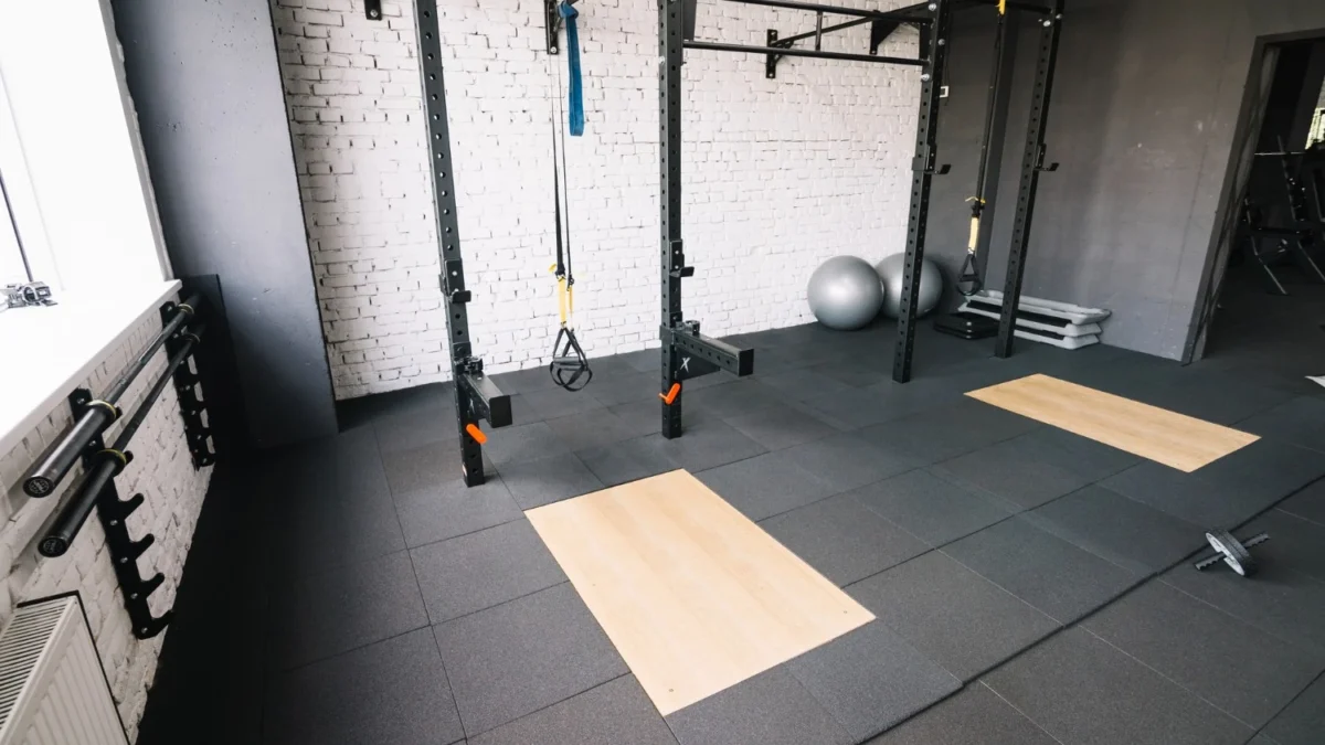 Worn rubber gym flooring showing signs of damage and wear that indicate it needs refinishing