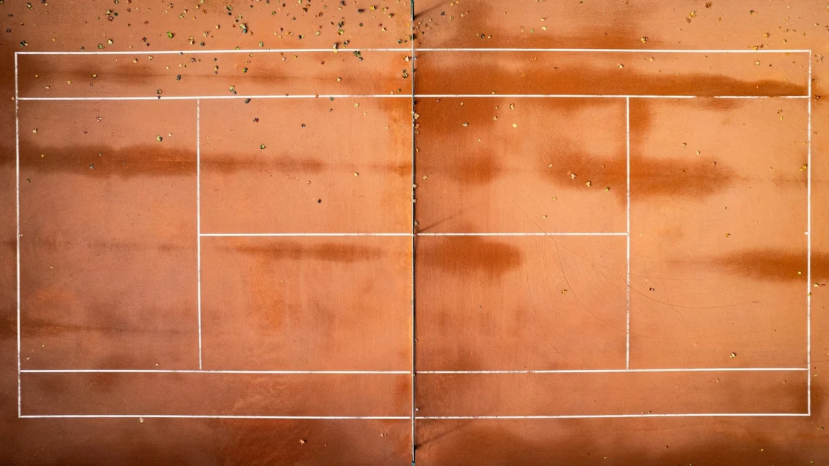 Outdoor tennis court with visible surface cracks undergoing professional tennis court crack repair and resurfacing.