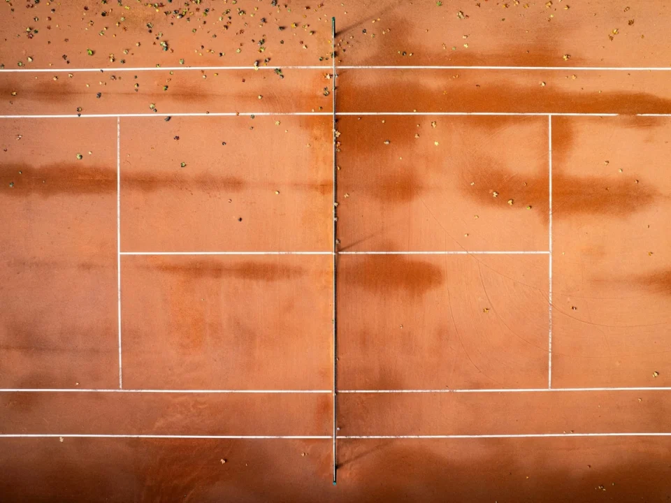Outdoor tennis court with visible surface cracks undergoing professional tennis court crack repair and resurfacing.