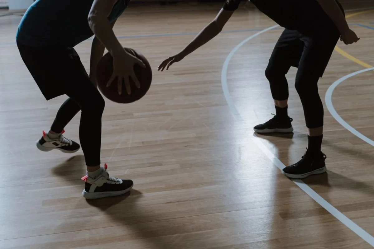 Polished maple hardwood basketball court flooring in an indoor gymnasium designed for durability, consistent ball response, and player safety.
