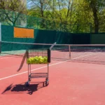 Outdoor tennis court showing surface cracks and faded court lines before professional tennis court resurfacing in Denver.